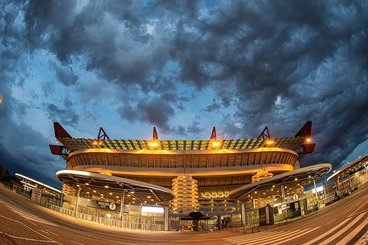 Floodlit San Siro exterior at dusk before a Milan stadium tour in Italy